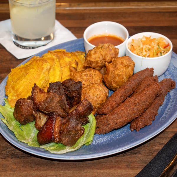 Paolo's Caribbean Fusion platter with fried pork, plantains, fritters, and two dipping sauces.
