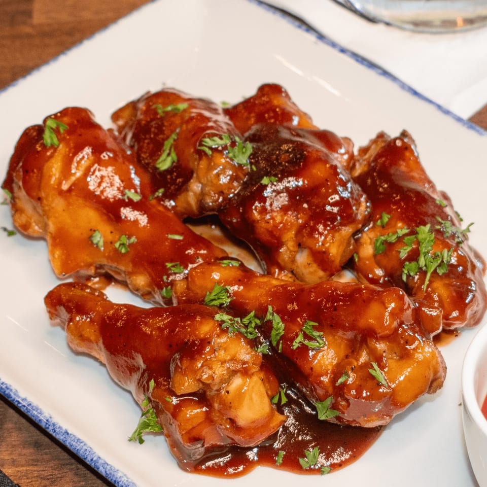 Paolo's Caribbean Fusion chicken wings, glazed in a rich, dark sauce and garnished with fresh parsley.