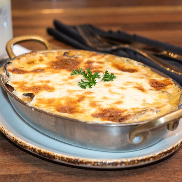 A golden-brown baked Caribbean casserole in a metal dish, garnished with fresh parsley.